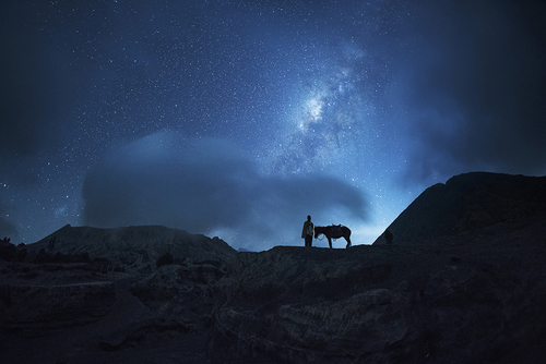 Horsemen standing near Erupting Volcano under million stars