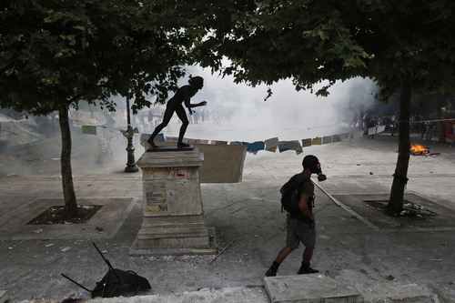 A Protester Walks in Front of a Replica Ancient Statue